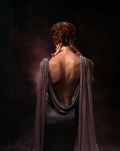 the back of a woman's dress is draped over her shoulders and it has an open neckline