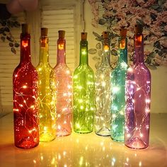 several bottles with lights in them sitting on a table