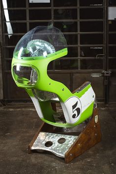 a green motorcycle helmet sitting on top of a wooden stand