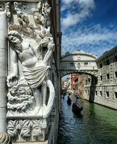 a statue on the side of a building next to a canal with gondolas