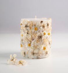 a white candle with yellow and white flowers on it