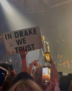 people holding up cell phones and signs in front of a crowd at a music concert