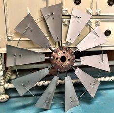 a large metal windmill sitting on top of a blue floor next to a white dresser