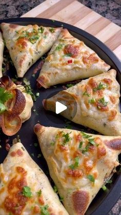 several pieces of pizza sitting on top of a black plate with green garnish