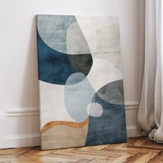 an abstract painting on the wall next to a wooden floor with a window in the background