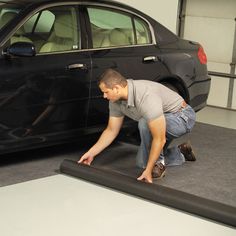 a man working on a black car in a garage with another man looking at it