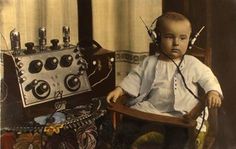 a young boy sitting in a chair with headphones on and an old fashioned machine behind him