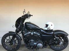 a black motorcycle parked in front of a wall with a helmet on it's seat