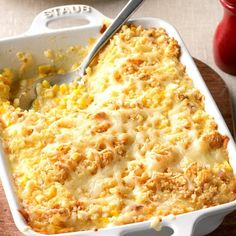 a casserole dish with meat and cheese in it on a wooden table next to a bottle of ketchup