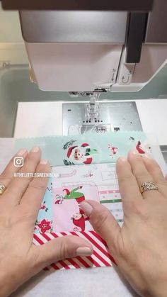 two hands are using a sewing machine to sew christmas cards