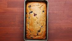 a loaf of blueberry bread in a metal pan on a wooden counter top,