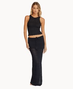 Woman wearing a matching black knit top and skirt in front of a white background. Fitted Beach Maxi Skirt, Fitted Maxi Skirt For Beach In Summer, Fitted Long Maxi Skirt For Beach, Fitted Summer Maxi Skirt For Beach, Fitted Maxi Skirt For Beach Season, Fitted Summer Maxi Skirt For The Beach, Fitted Summer Maxi Skirt, Versatile Summer Maxi Skirt, Fitted Long Beach Skirt