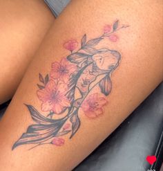 a woman's thigh with flowers and a koi fish tattoo on her leg