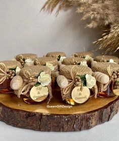 several small jars filled with honey sitting on top of a wooden slab next to flowers