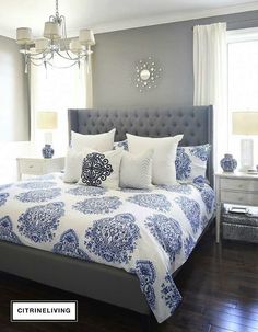 a large bed with blue and white comforters in a gray room next to a window