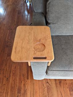 a wooden table sitting on top of a couch next to a gray sofa chair with an apple logo on it