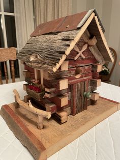 a small wooden house sitting on top of a table next to a white tablecloth