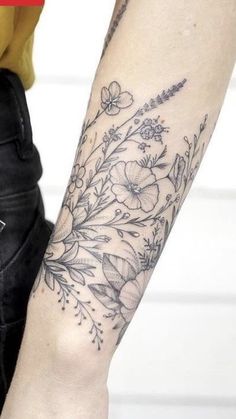 a woman's arm with flowers and leaves tattooed on the left side of her arm