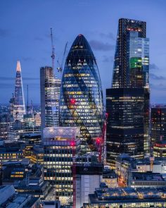 the london skyline at night with skyscrapers lit up in red and blue colors, including the ghere