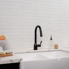 a white kitchen sink with black faucet and soap dispenser