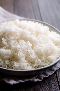 white rice in a bowl on top of a wooden table next to a cloth napkin