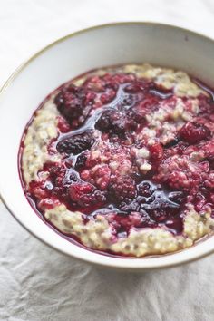 a bowl filled with oatmeal and berries on top of a white cloth