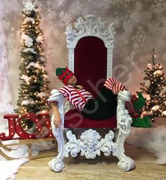 a man sitting on top of a red chair next to a christmas tree