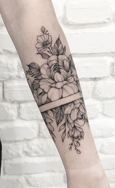 a black and white flower tattoo on the left arm with a ribbon wrapped around it