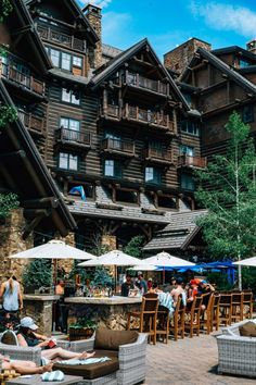 people are sitting at tables in front of a large wooden building with many windows and balconies