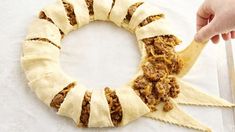 a person holding a wooden spoon in front of a doughnut shaped like a wreath