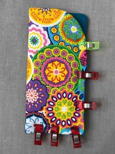 a colorful notebook with clips attached to it on a gray surface next to a pair of scissors