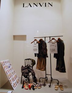 clothes are hanging on racks in front of a store window with mannequins and other items