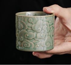 a person holding a green cup in their left hand, with swirls on it