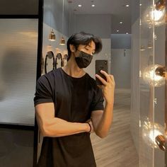 a man taking a selfie in front of a mirror wearing a face mask and holding a cell phone