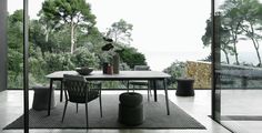 a dining room table and chairs in front of glass doors with trees on the other side