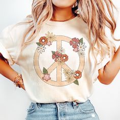 a woman wearing a peace sign t - shirt with flowers on it