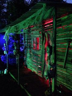 a wooden cabin lit up at night with green and red lights on the side of it