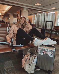 a woman sitting on top of a bench next to an airport luggage bag and suitcase