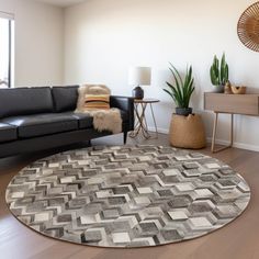 a living room with black leather couches and a round rug