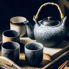 a tea set is sitting on a tray with chopsticks and two cups next to it