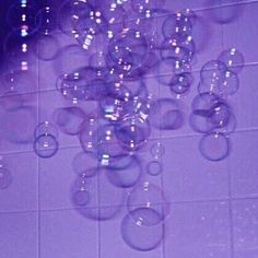 soap bubbles floating in the air on a tiled floor with purple walls and white tiles