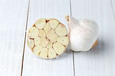 an onion and garlic on a white wooden surface with the peel cut off to look like it is sliced in half