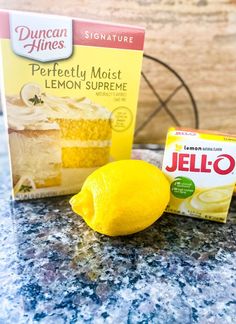 two boxes of jello next to a lemon on a table with a piece of cake