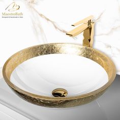 a bathroom sink with gold faucet and marble counter top