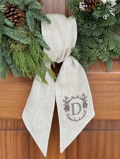 a christmas wreath with pine cones and evergreen leaves on it, hanging from the front door