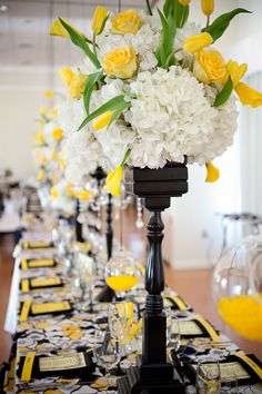 a long table with yellow and white flowers in vases on top of each other