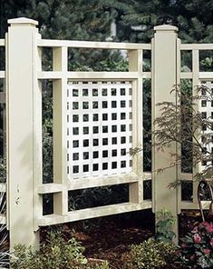 an image of a white fence with flowers in the foreground and trees in the background