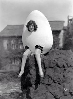 a woman sitting on top of a rock next to an egg