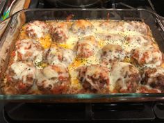 a casserole dish with meatballs and cheese in it sitting on the stove