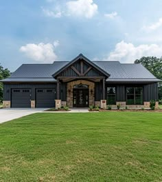 a large black house with two garages on the front and side of it, surrounded by lush green grass